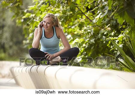 Woman chatting on smartphone on stone seating View Large Photo Image Stock Image - Woman chatting on smartphone on stone seating. Fotosearch