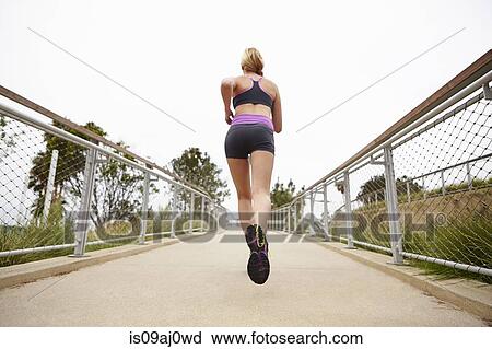 Stock Image - Woman running on bridge. Fotosearch