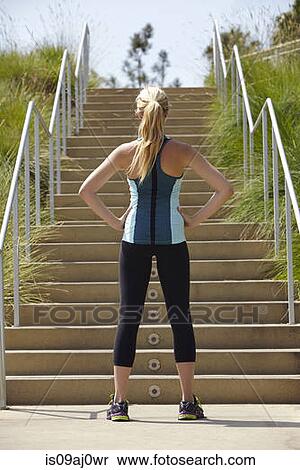 Stock Photography - Woman standing at base of stairs. Fotosearch