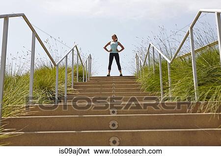 Stock Photograph - Woman standing at top of stairs. Fotosearch