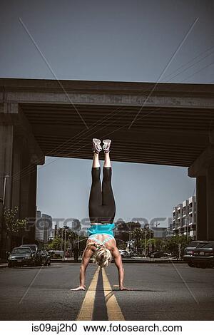 Young adult woman doing handstand in road View Large Photo Image Stock Image - Young adult woman doing handstand in road. Fotosearch