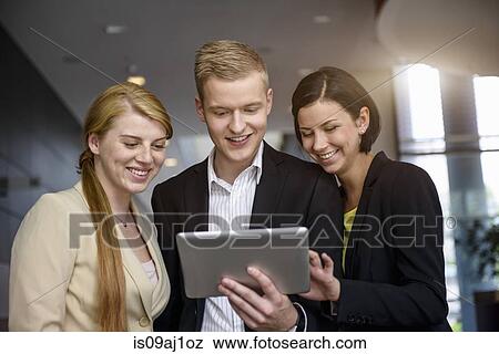 Stock Photo - Young businessman and women using touchscreen on digital tablet in office. Fotosearch
