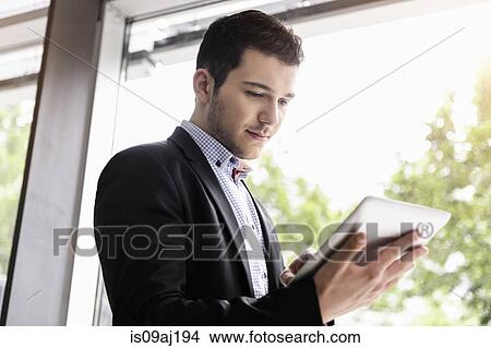 Young businessman in office using digital tablet View Large Photo Image Picture - Young businessman in office using digital tablet. Fotosearch