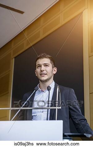 Stock Photograph - Young businessman speaking in conference room. Fotosearch