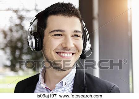 Young businessman using telephone headset in office View Large Photo Image Stock Photo - Young businessman using telephone headset in office. Fotosearch