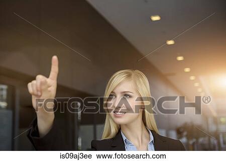 Stock Image - Young businesswoman signaling with finger in office. Fotosearch