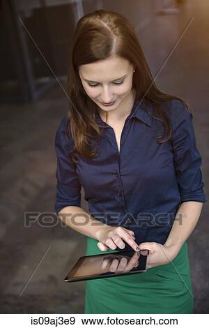 Stock Photo - Young businesswoman using digital tablet in office. Fotosearch