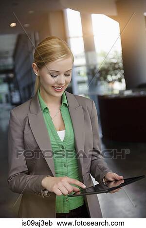 Young businesswoman using touchscreen on digital tablet in office View Large Photo Image Stock Image - Young businesswoman using touchscreen on digital tablet in office. Fotosearch