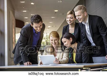 Stock Photography - Young businesswomen and men looking at digital tablet in office. Fotosearch