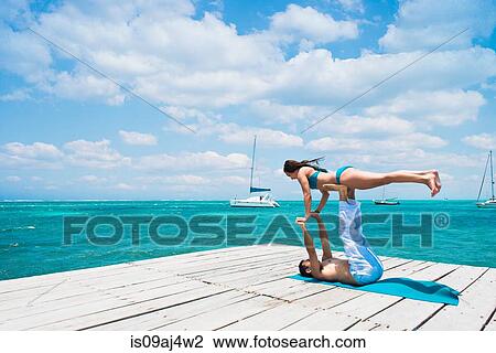 Stock Image - Young couple in airplane pose on pier, San Pedro, Belize. Fotosearch