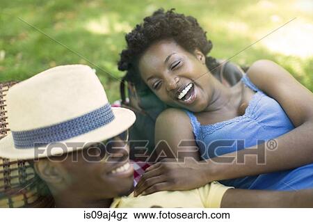 Stock Photo - Young couple in lying in park laughing together. Fotosearch