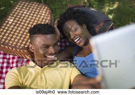 Young couple in lying in park taking a selfie on digital tablet View Large Photo Image Stock Image - Young couple in lying in park taking a selfie on digital tablet. Fotosearch