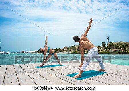 Young couple in triangle pose on pier, San Pedro, Belize View Large Photo Image Picture - Young couple in triangle pose on pier, San Pedro, Belize. Fotosearch