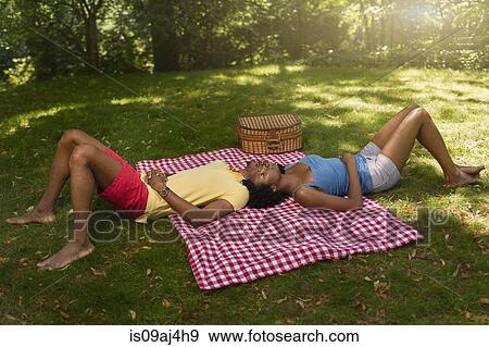 Young couple lying on picnic blanket in park on opposite sides View Large Photo Image Stock Photo - Young couple lying on picnic blanket in park on opposite sides. Fotosearch