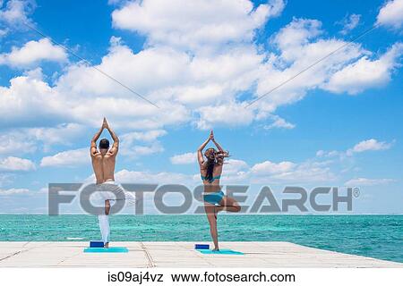 Young couple practising yoga on pier, San Pedro, Belize View Large Photo Image Stock Photo - Young couple practising yoga on pier, San Pedro, Belize. Fotosearch