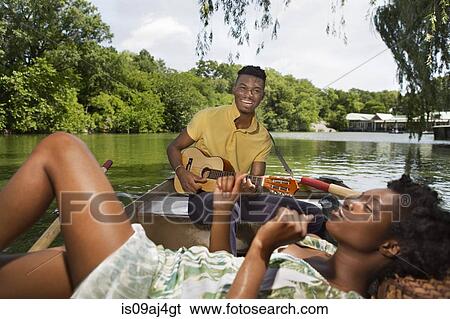 Stock Photograph - Young couple relaxing in rowing boat on lake in Central Park, New York City, USA. Fotosearch