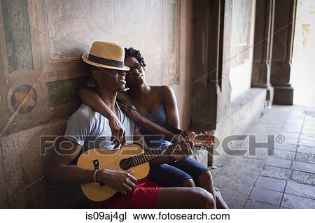 Stock Image - Young couple sitting with mandolin in Bethesda Terrace arcade, Central Park, New York City, USA. Fotosearch