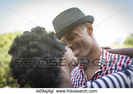 Young couple smiling and hugging in park View Large Photo Image Stock Image - Young couple smiling and hugging in park. Fotosearch