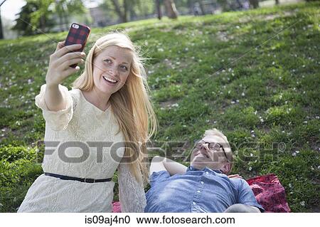 Young couple taking selfie with smartphone in park View Large Photo Image Stock Image - Young couple taking selfie with smartphone in park. Fotosearch