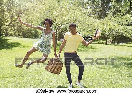 Young couple with picnic basket in park, with female jumping mid air View Large Photo Image Stock Photo - Young couple with picnic basket in park, with female jumping mid air. Fotosearch