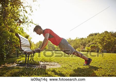 Young male runner doing push ups on park bench View Large Photo Image Stock Photography - Young male runner doing push ups on park bench. Fotosearch
