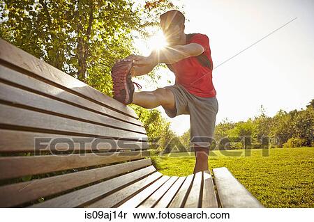 Young male runner stretching legs on park bench View Large Photo Image Stock Photography - Young male runner stretching legs on park bench. Fotosearch