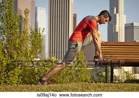 Picture - Young male runner stretching on park bench. Fotosearch