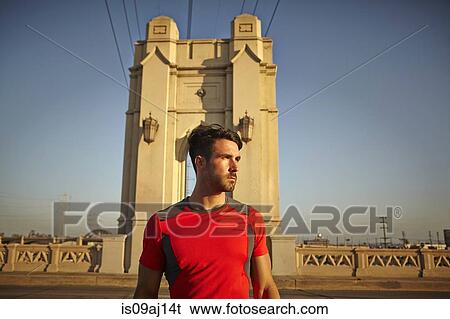Stock Photograph - Young male runner taking a break at city bridge. Fotosearch