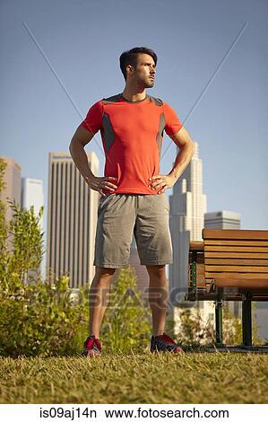 Picture - Young male runner taking a break in park. Fotosearch
