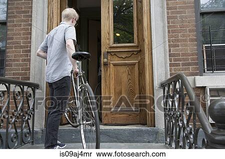 Young man carrying bicycle up steps to front door View Large Photo Image Stock Photography - Young man carrying bicycle up steps to front door. Fotosearch