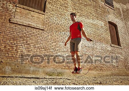 Young man exercising with skipping rope on wasteland View Large Photo Image Stock Image - Young man exercising with skipping rope on wasteland. Fotosearch