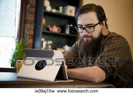Young man having coffee and using digital tablet in cafe View Large Photo Image Stock Photo - Young man having coffee and using digital tablet in cafe. Fotosearch