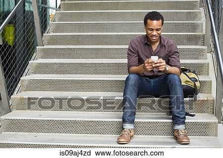Young man texting on smartphone on city stairway View Large Photo Image Stock Image - Young man texting on smartphone on city stairway. Fotosearch