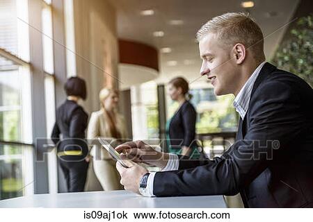 Young man using touchscreen on digital tablet in office View Large Photo Image Stock Image - Young man using touchscreen on digital tablet in office. Fotosearch
