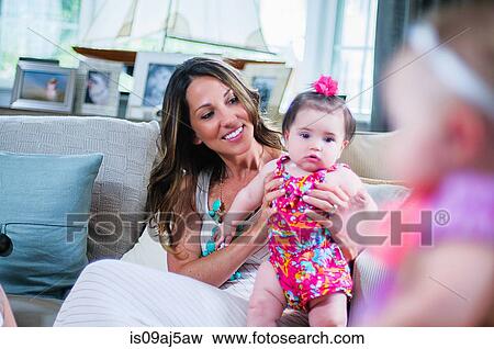 Stock Photo - Young mother with baby girl in sitting room. Fotosearch