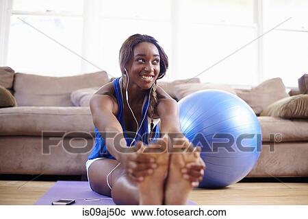 Young woman exercising and touching toes on sitting room floor View Large Photo Image Stock Image - Young woman exercising and touching toes on sitting room floor. Fotosearch