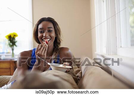 Young woman on a training break, eating fruit on sofa View Large Photo Image Stock Photography - Young woman on a training break, eating fruit on sofa. Fotosearch