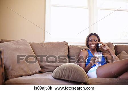 Young woman on a training break, chatting on smartphone in sitting room View Large Photo Image Stock Image - Young woman on a training break, chatting on smartphone in sitting room. Fotosearch