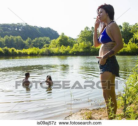 Stock Photo - Young woman smoking cigarette on canal bank, Delaware Canal State Park, New Hope, Pennsylvania, USA. Fotosearch