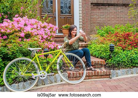 Young woman taking self portrait on smartphone on house steps View Large Photo Image Stock Photography - Young woman taking self portrait on smartphone on house steps. Fotosearch