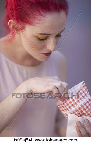 Stock Photograph - Young woman with pink hair eating takeaway food. Fotosearch