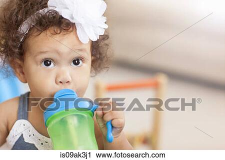 Stock Image - Baby girl drinking from sippy cup. Fotosearch