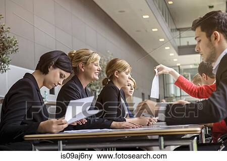 Stock Photo - Business colleagues doing paperwork and brainstorming. Fotosearch