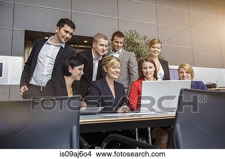 Businesswoman and office team looking at laptop View Large Photo Image Picture - Businesswoman and office team looking at laptop. Fotosearch