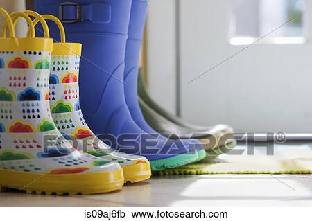 Stock Image - Close up side view of row of rubber boots at back door. Fotosearch