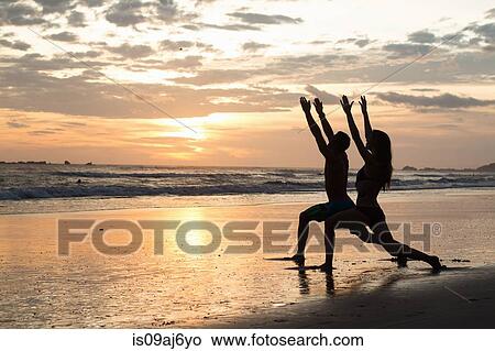 Couple doing stretching exercises on beach at sunset, Nosara, Guanacaste, Costa Rica View Large Photo Image Picture - Couple doing stretching exercises on beach at sunset, Nosara, Guanacaste, Costa Rica. Fotosearch