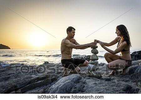Picture - Couple on beach building tower from rocks. Fotosearch