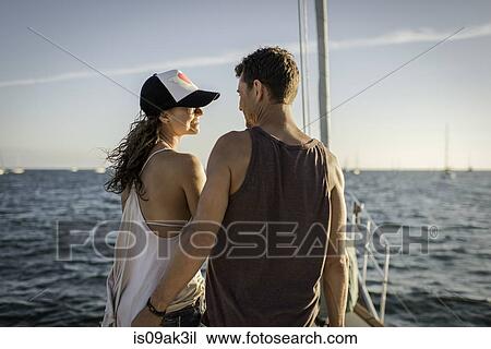 Stock Image - Couple on boat in ocean, rear view. Fotosearch