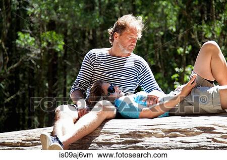 Couple relaxing on forest tree trunk in sunlight View Large Photo Image Picture - Couple relaxing on forest tree trunk in sunlight. Fotosearch