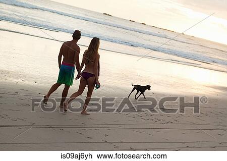 Stock Image - Couple strolling hand in hand on beach, Nosara, Guanacaste, Costa Rica. Fotosearch
